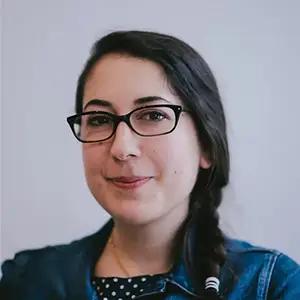 Producer Elhum Shakerifar, with a dark side braid and black glasses, in a denim jacket.