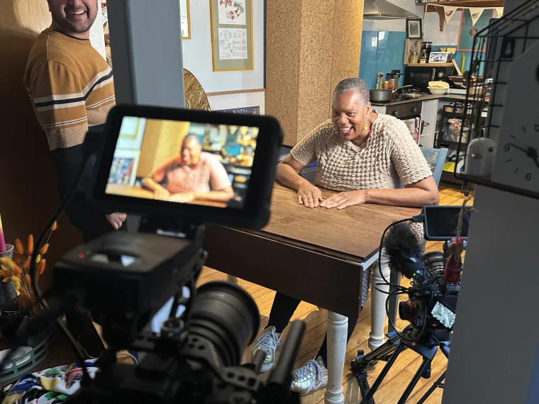 Kemi being filmed at her kitchen table during an interview, behind the scenes on Farming: Kemi's Story.