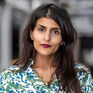 Filmmaker Jayisha Patel, with long dark hair, wearing a floral top and gold necklace.