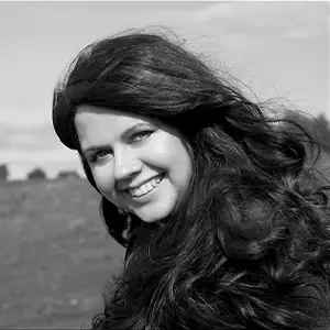 Producer-director Lindsey Dryden, smiling, with long dark wavy hair, in a black-and-white portrait.