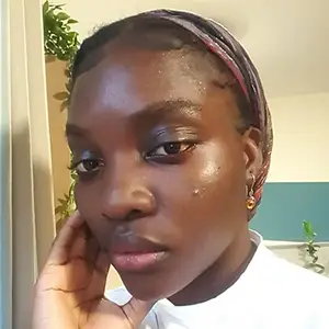 Filmmaker Simisola Akande, a young Black woman with braided hair, resting her hand against her cheek.